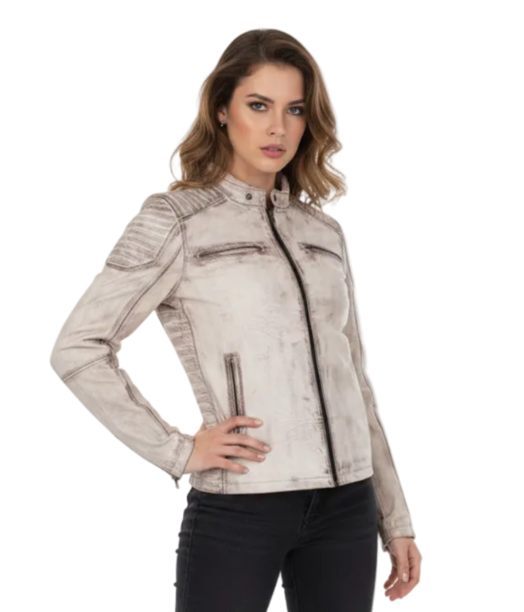 A woman modeling a light beige distressed motorcycle jacket with black zippers, paired with black skinny jeans and black ankle boots, against a plain white studio background.